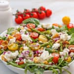 goat cheese asparagus salad in bowl with tomatoes in background