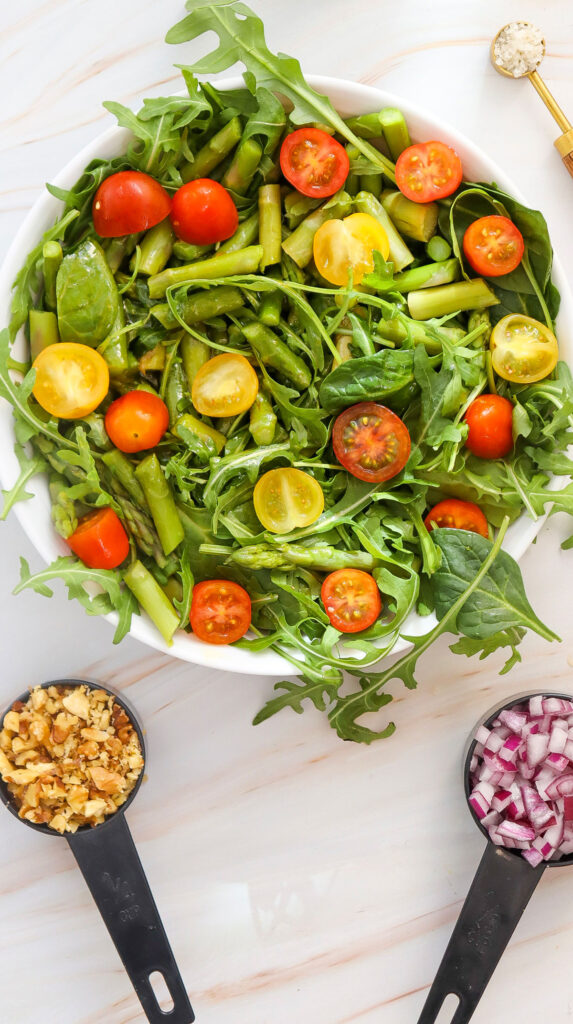 asparagus salad with diced onions and walnuts in measuring cups nearby