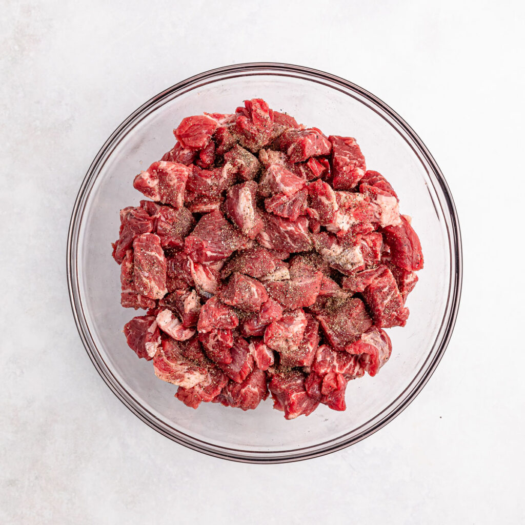 beef chunks with seasonings in glass bowl