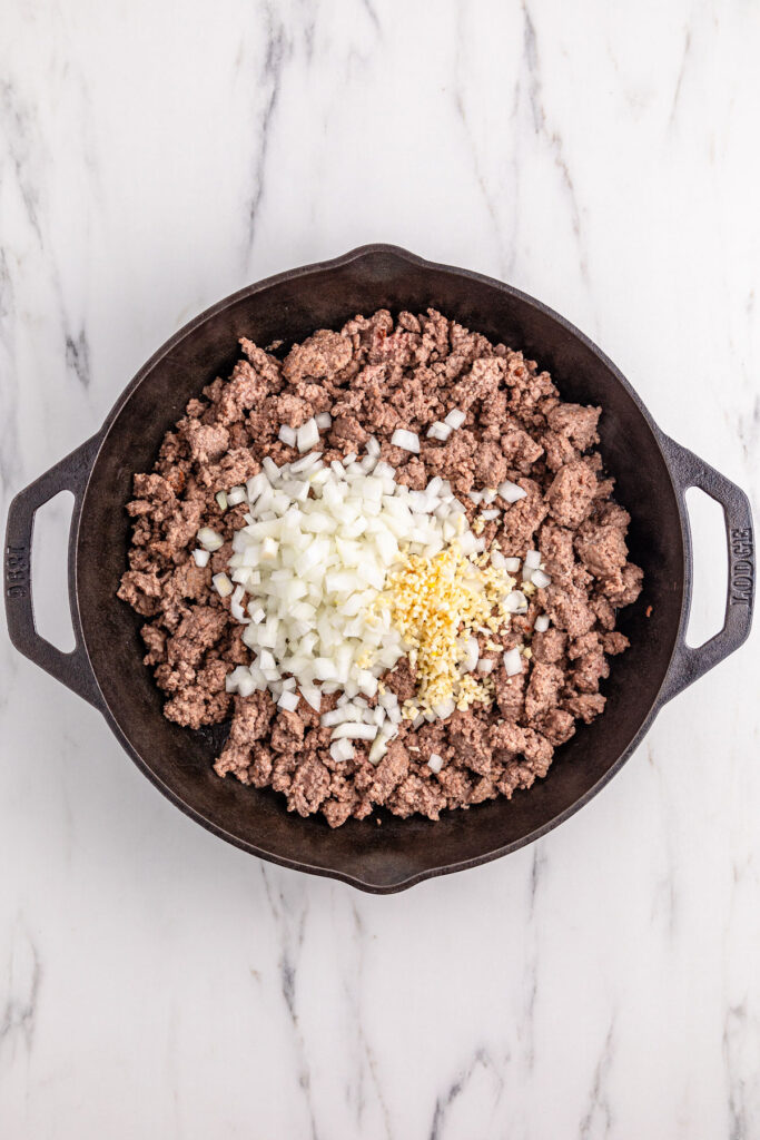 ground beef and onions in cast iron skillet for chili