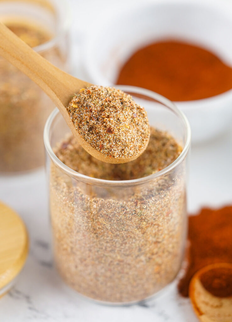 spoon scooping Jamaican jerk seasoning out of glass jar