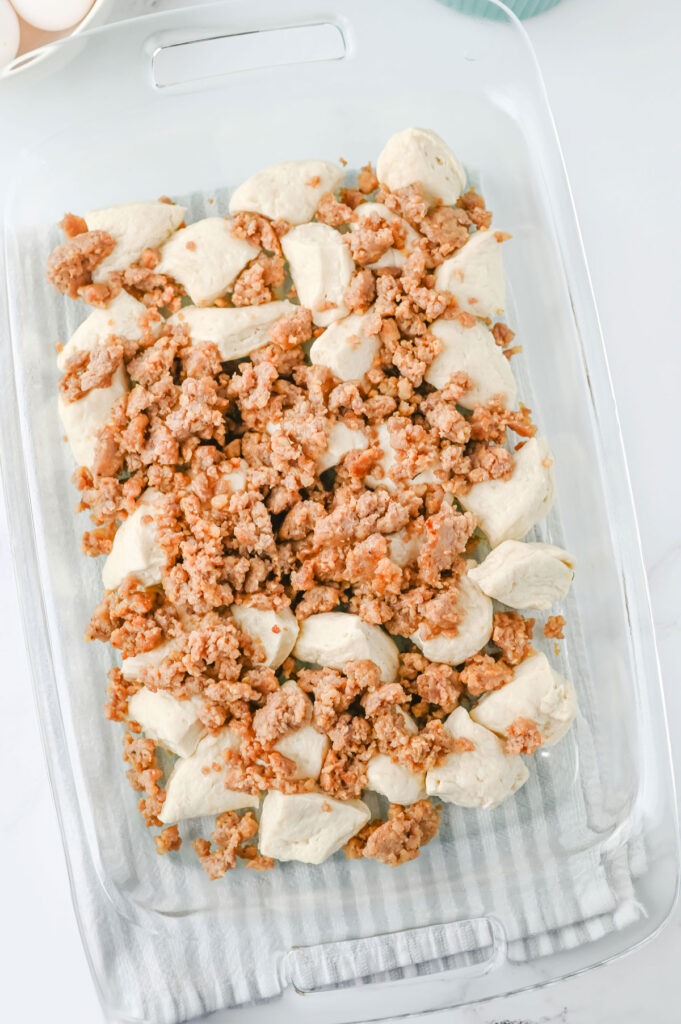 biscuit dough pieces and browned sausage in casserole dish