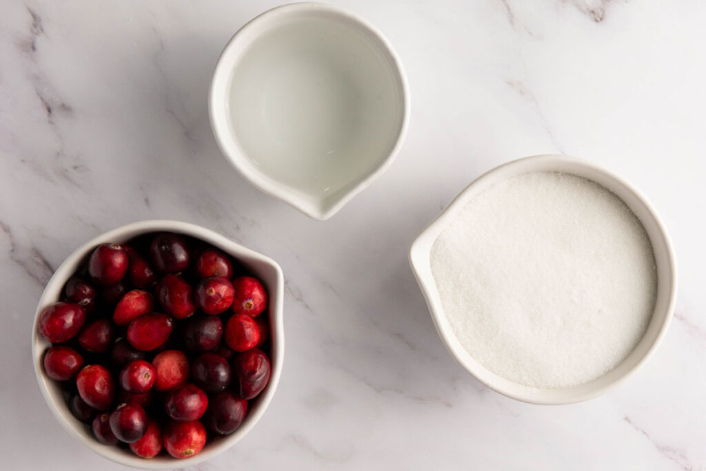 sugared cranberries ingredients in bowls on marble countertop