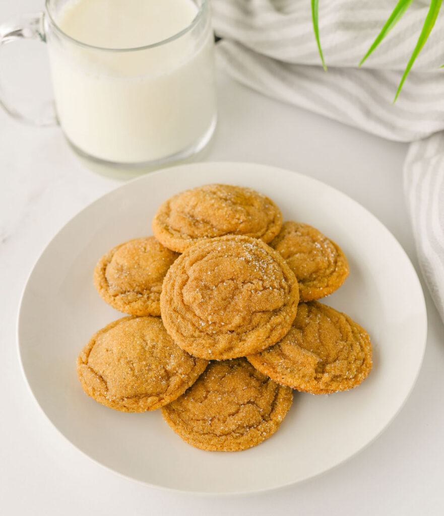 chewy ginger molasses cookies on white plate with glass of milk