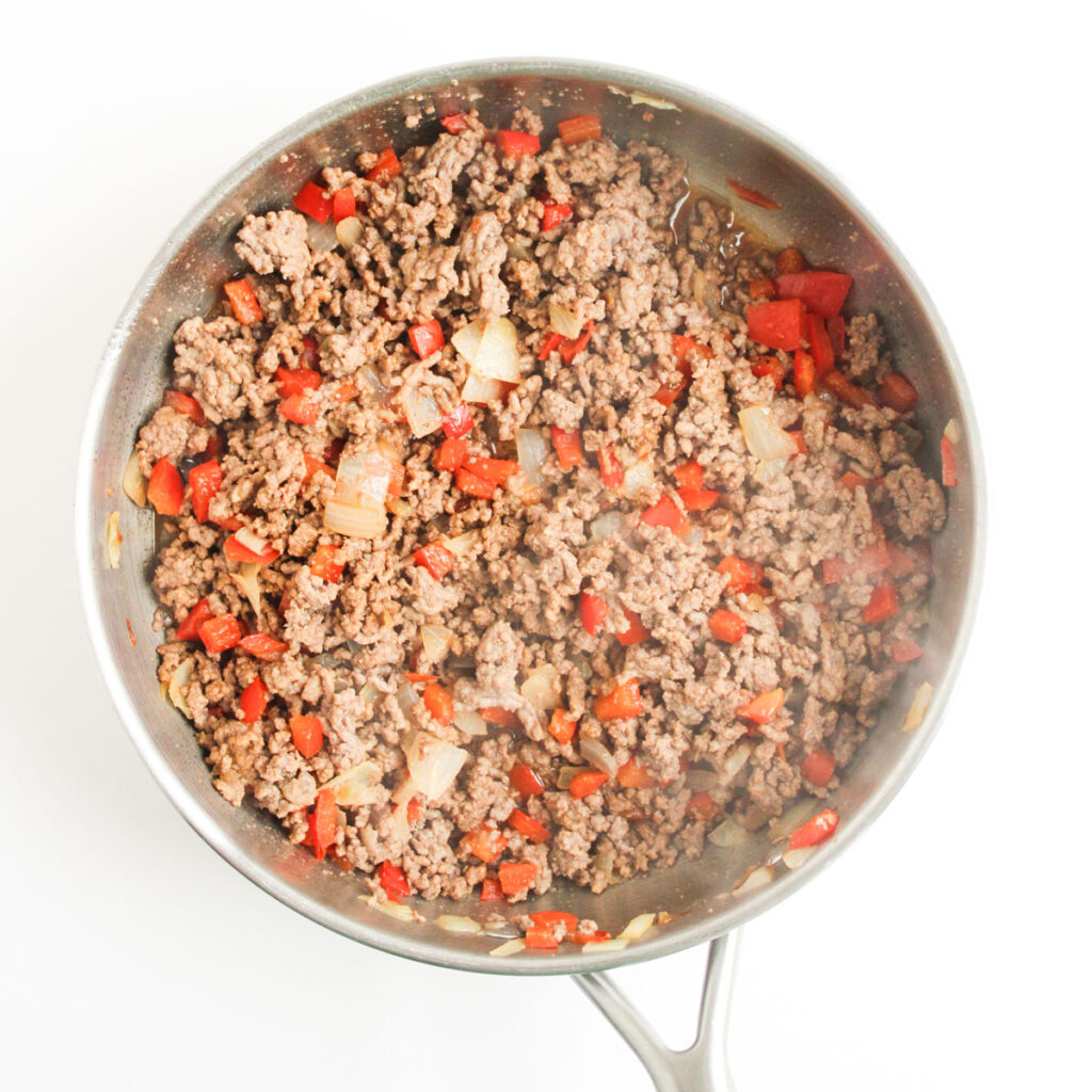 ground beef with diced peppers and onions in pan