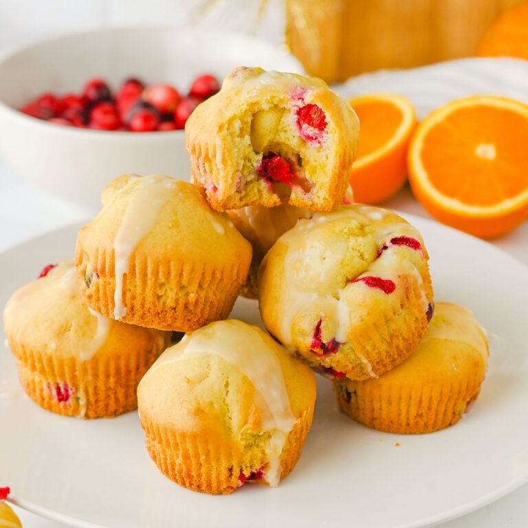 stacked cranberry orange muffins with top one bitten into