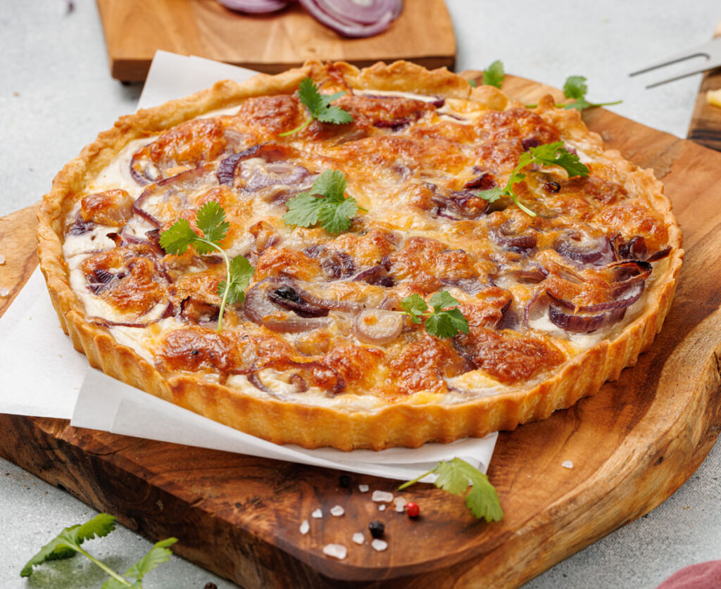 onion tart on parchment paper covered cutting board