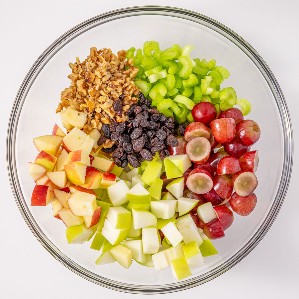waldorf salad ingredients in glass bowl before mixing