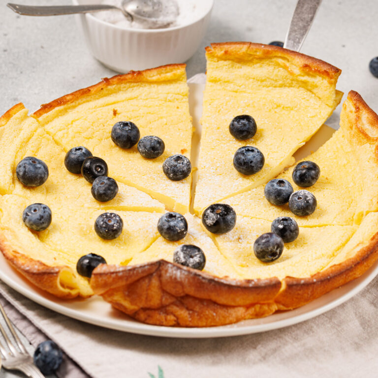 dutch baby pancake sliced and topped with blueberries