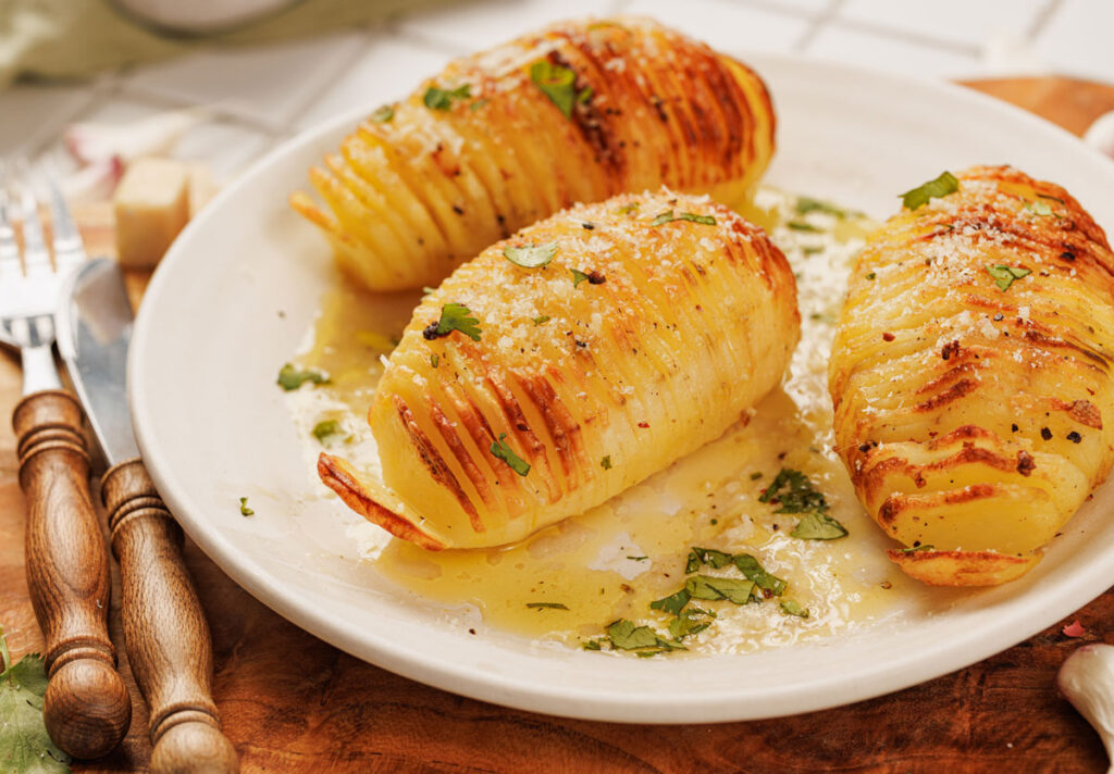 three hasselback potatoes on white plate