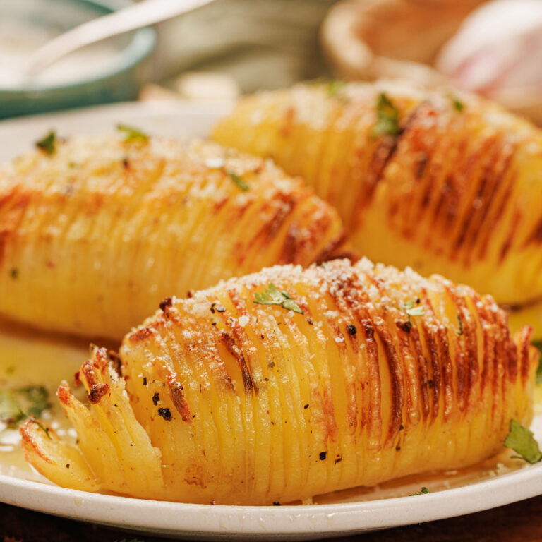 three hasselback potatoes on white plate