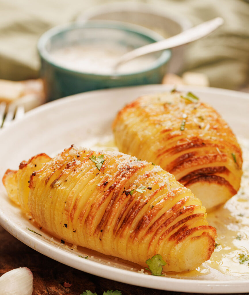 two hasselback potatoes on white plate