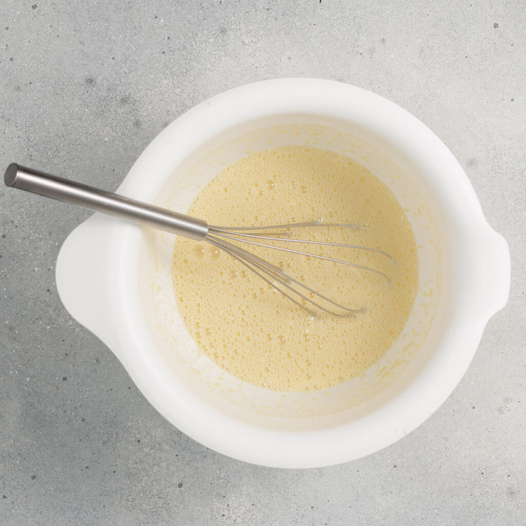 dutch baby pancake batter in white bowl with whisk