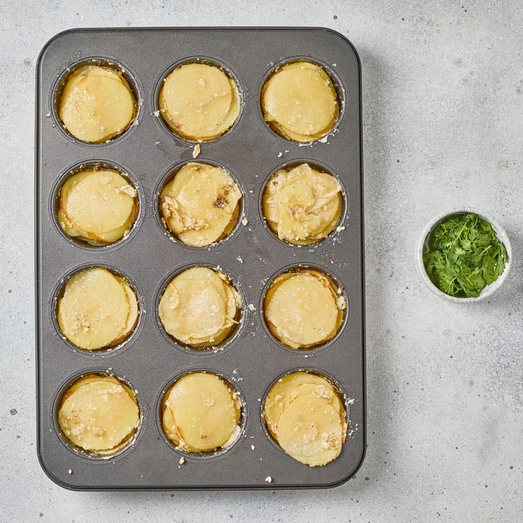 potato slices stacked in muffin tin
