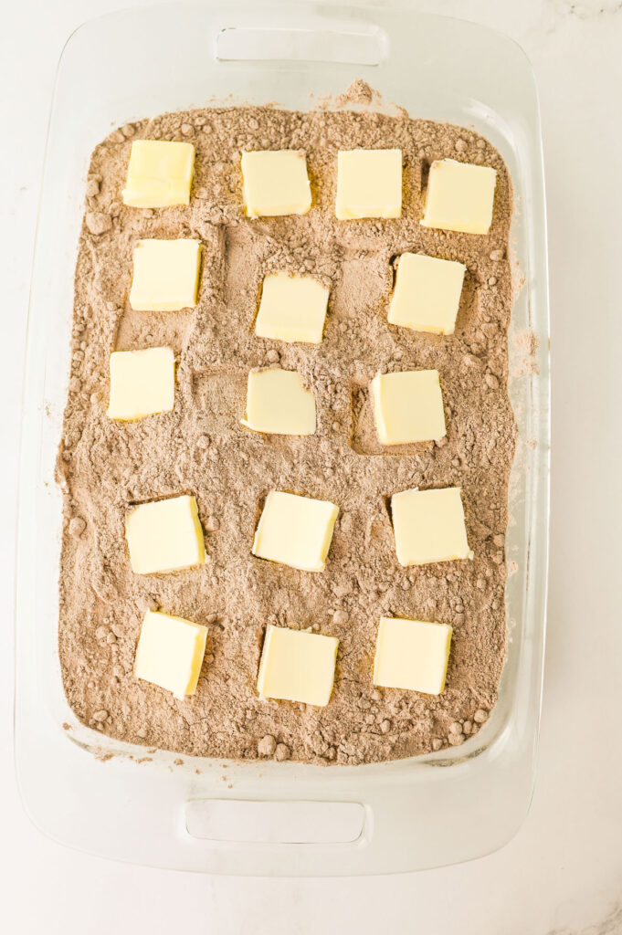 oreo dump cake with dry cake mix and pats of butter on top