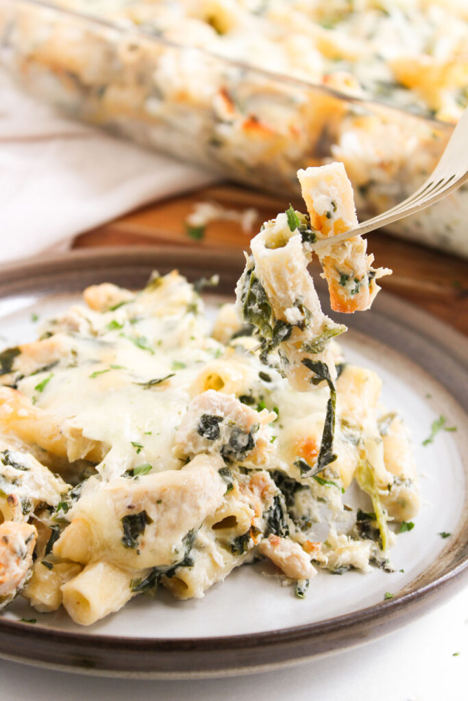 fork lifting bite of spinach Artichoke Chicken Casserole from plate