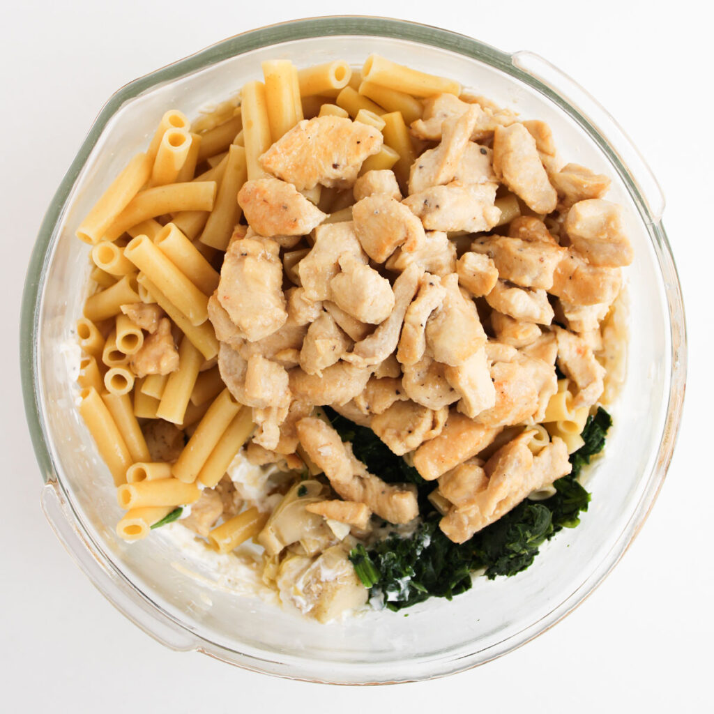 chicken, spinach, and pasta in glass bowl for making spinach Artichoke Chicken Casserole