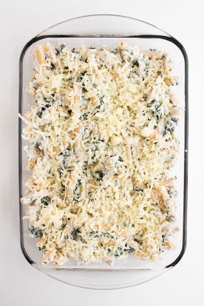 spinach Artichoke Chicken Casserole before baking topped with cheese