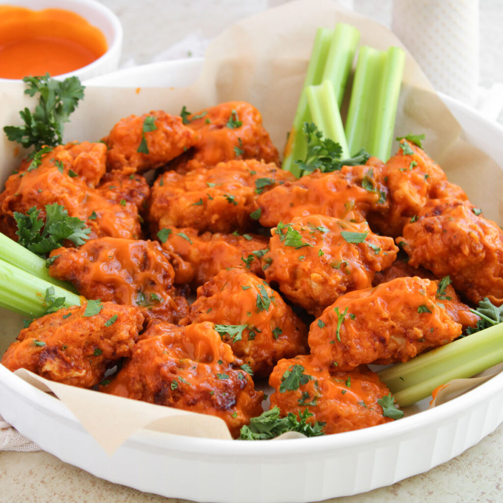 boneless buffalo wings and celery on white plate